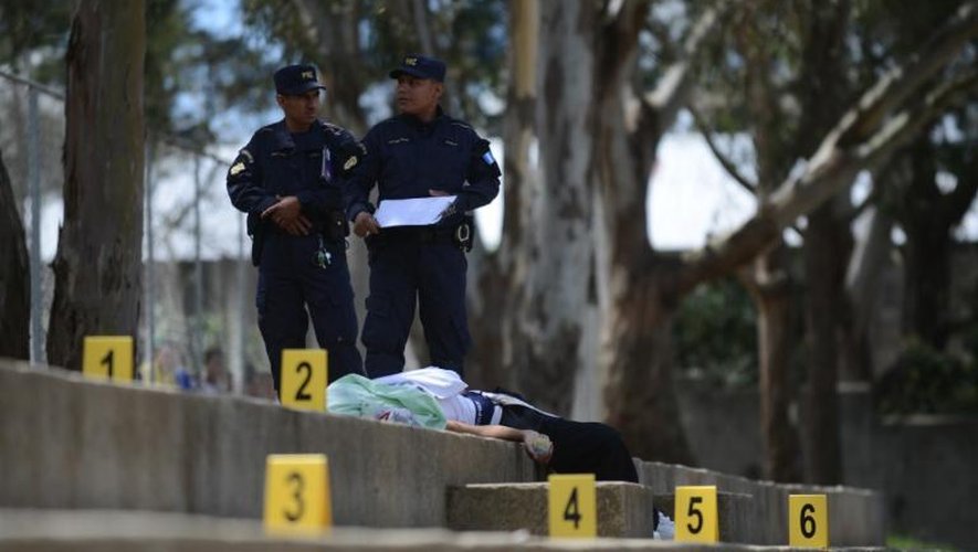 Des policiers guatémaltèques se tiennent près du corps d'un adolescent de 16 ans abattu par un gang, près de la capitale, le 13 juin 2013