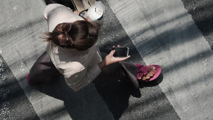 Une femme regarde son téléphone tout en traversant la rue