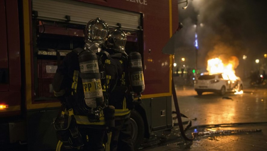 Des pompiers interviennent sur une voiture de police en feu place de la République à Paris, le 23 avril 2016