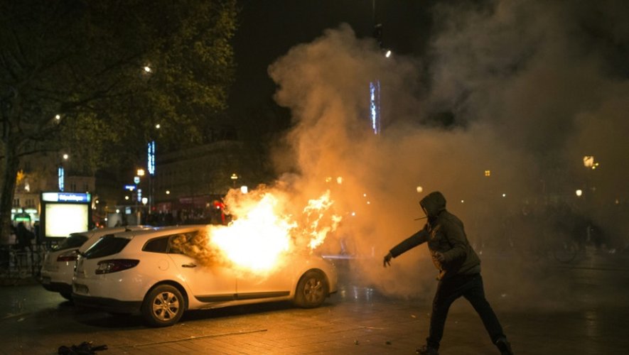 Un homme jette un projectile sur une voiture de police en feu place de la République à Paris, le 23 avril 2016