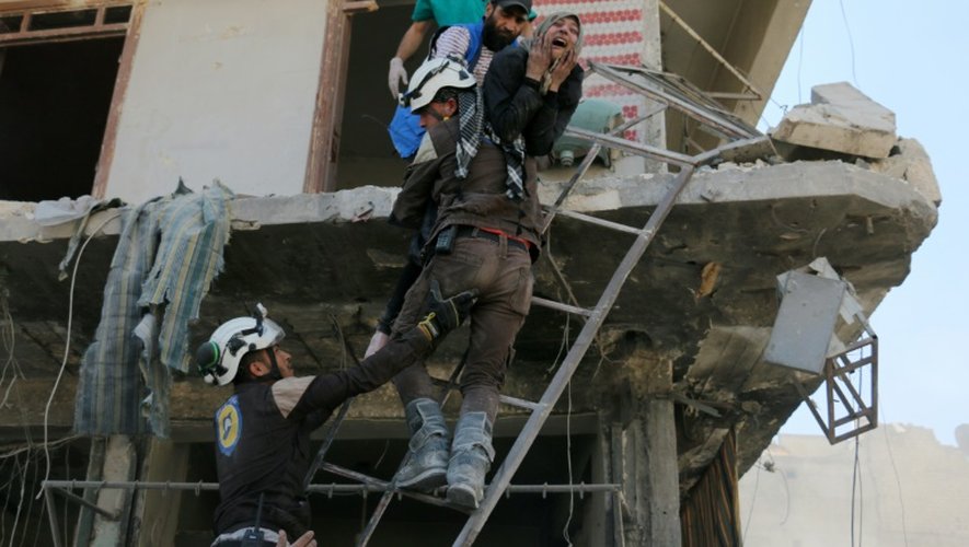 Des bénévoles du service de défense civil syrien évacuent des habitants d'un immeuble détruit par des bombardements, dans un quartier rebelle d'Alep le 23 avril 2016