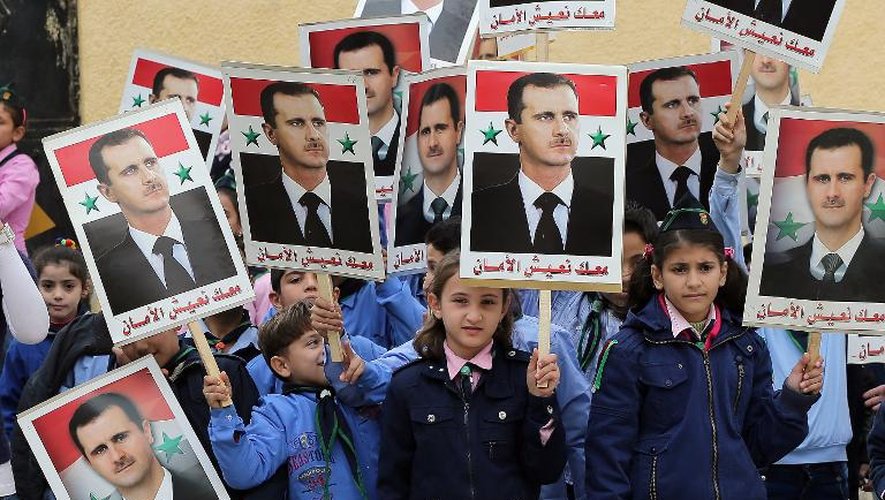Des enfants syriens brandissent des portraits du président Bachar al-Assad lors d'un rassemblement en faveur du parti au pouvoir Baath dans une école d'Aleppo, dans le nord du pays, dans une région contrôlée par le régime, le 17 novembre 2014