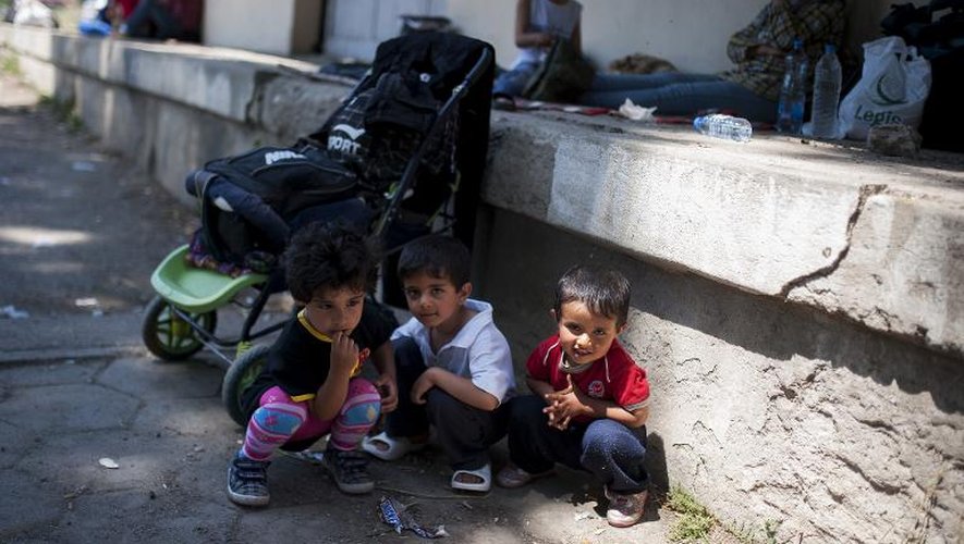 Trois enfants jouent pendant que leurs parents se reposent dans la gare de Demir Kapija, le 15 juin 2015, en Macédoine, en route vers la frontière de la Serbie