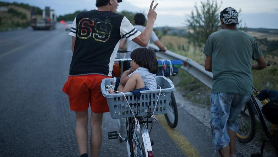 Un groupe de migrants pousse leurs vélos sur une route, le 15 juin 2015, près de la ville de Veles en Macédoine, en route vers la Serbie