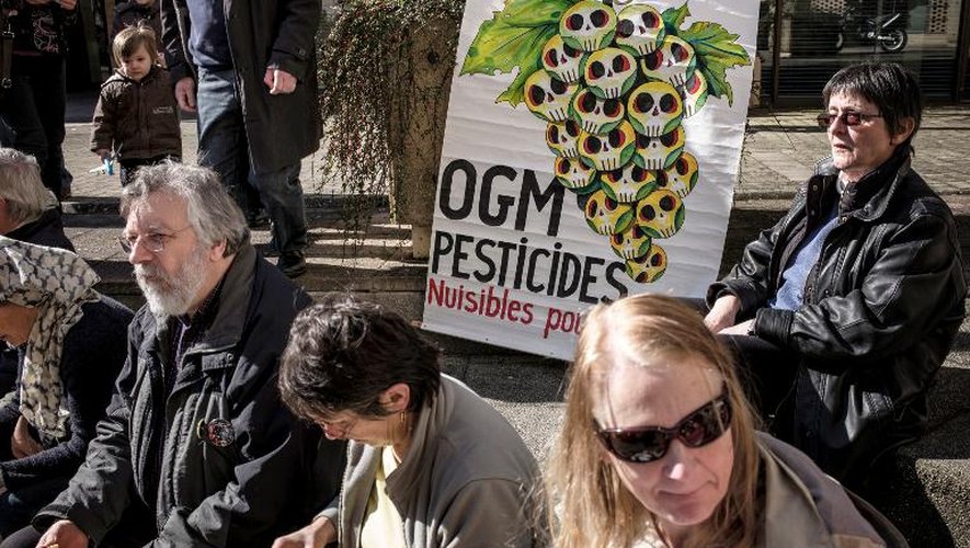 Une affiche dénonçant l'usage dangereux des OGM et des pesticides dans l'agriculture et des supporters du viticulteur bio Emmanuel Giboulot le 24 février 2014 à Dijon devant le tribunal où il était jugé pour avoir refusé de traiter