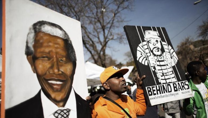 Un homme tient des posters à la gloire de Nelson Mandela, le 27 juin 2013 devant la clinique de Pretoria où est hospitalisé l'ancien président sud-africain