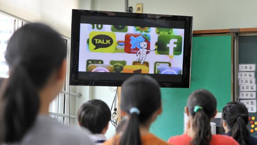 Des enfants sud-coréens regardent une émission sur les dangers de l'addiction aux smartphones, le 11 juin 2013 dans le sud de Séoul