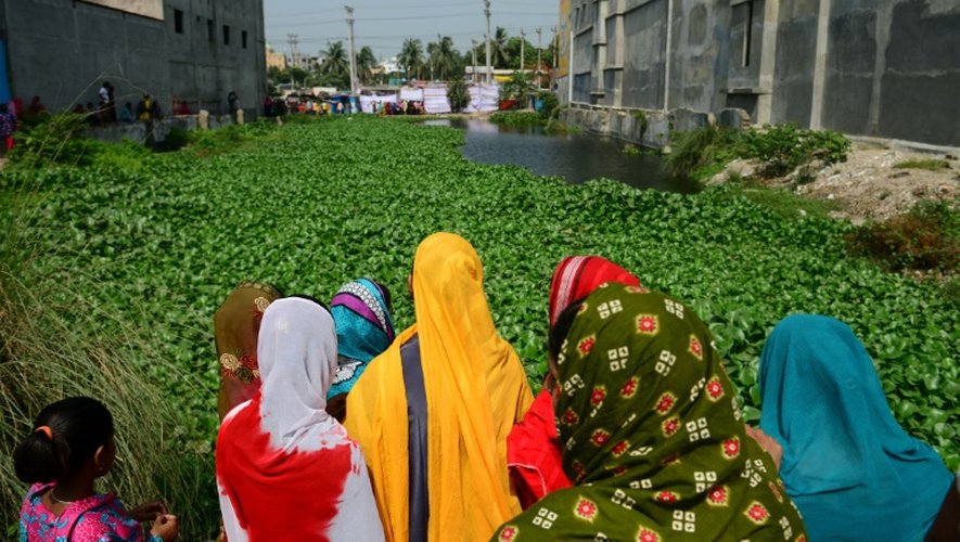 Des femmes bangladaises regardent le 24 avril 2016 le site où s'est effondré le bâtiment du Rana Plaza il y a trois ans, dans lequel plus de 1.100 personnes avaient trouvé la mort, près de Dhaka