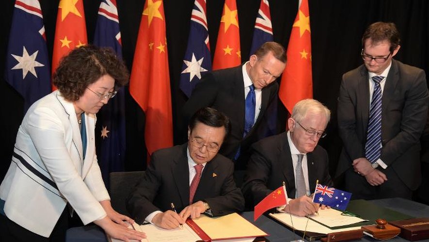 Le Premier ministre australien Tony Abbott (centre, debout) regarde le ministre chinois du commerce Gao Hucheng (2e g) et de l'Australie Andrew Robb (2e d) signer l'accord de libre-échange entre leurs deux pays