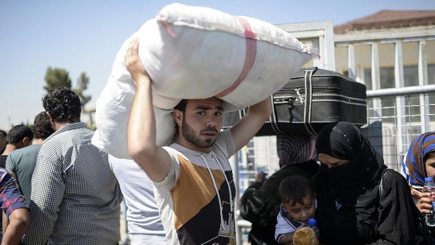 Des réfugiés syriens à la frontière turque s'apprêtent à rentrer chez eux après la perte de la ville de Tall Abyad par le groupe EI, le 17 juin 2015