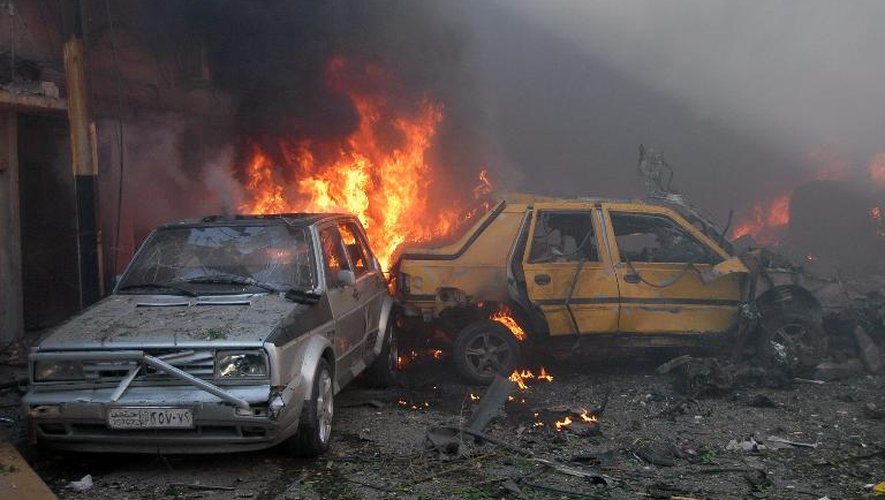 Des véhicules en feu après l'explosion de voiture spiégées dans le centre de Homs, en Syrie le 9 avril 2014