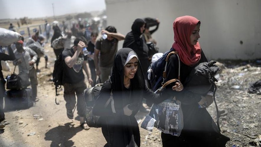 Des réfugiés syriens fuient les combats entre les forces kurdes et les jihadistes de l'EI en Syrie et passent la frontière avec la Turquie, le 15 juin 2015
