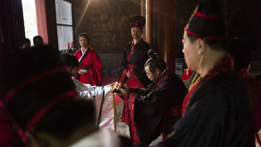 Zhen Zhongyi (c), doyen de l'Académie des beaux-arts du Hebei, remet son diplôme à une étudiante, lors d'une cérémonie dédiée au grand penseur Confucius