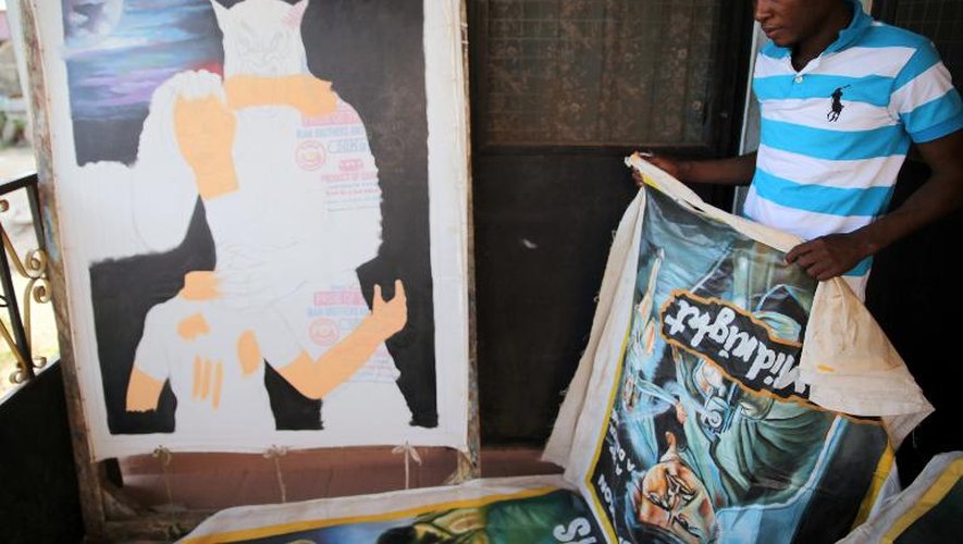 Oka Afutu, peintre spécialisé dans les affiches de films, déroule un poster dans son atelier à Accra, en mars 2014