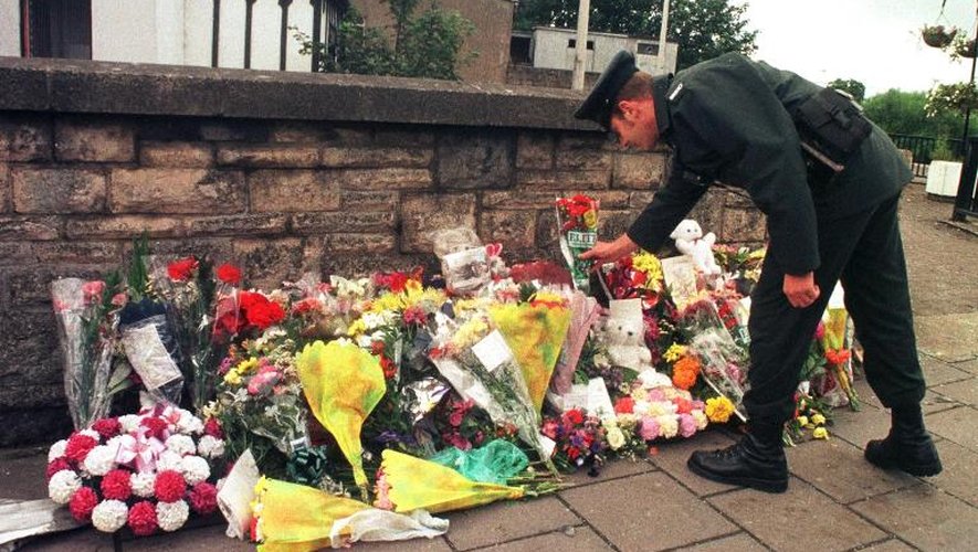 Un officier de la Royal Ulster Constabulary dépose des fleurs devant le site d'un attentat à Omagh le 17 août 1998