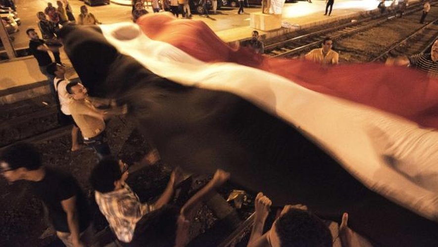 Des opposants au président Morsi portent le drapeau national, le 29 juin 2013, devant le palais présidentiel au Caire