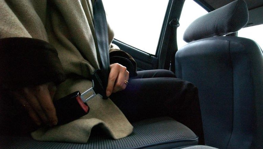 Une personne attache sa ceinture de sécurité à l'arrière d'un véhicule