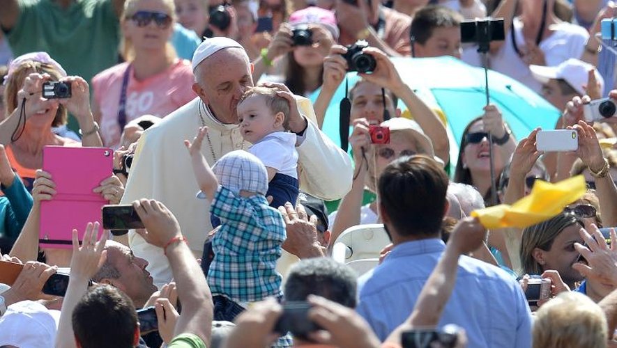 Le pape François bénit un bébé en arrivant à l'audience générale au Vatican le 17 juin 2015