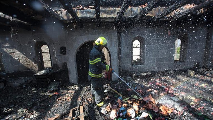 Un pompier éteint le 18 juin 2015 les derniers foyers de l'incendie ayant ravagé le sanctuaire chrétien de Tabgha en Israël, sur les rives du lac de Tibériade