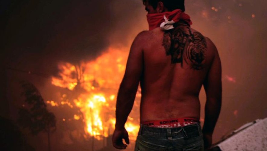 Un homme devant des habitations en flammes le 12 avril 2014 à Valparaiso