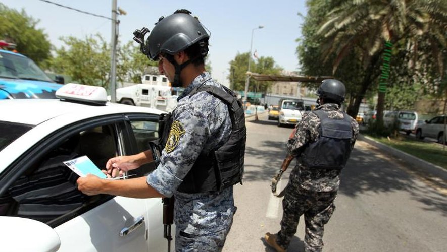 Des policiers vérifient des documents lors d'un barrage routier à Bagdad, le 1er juillet 2013