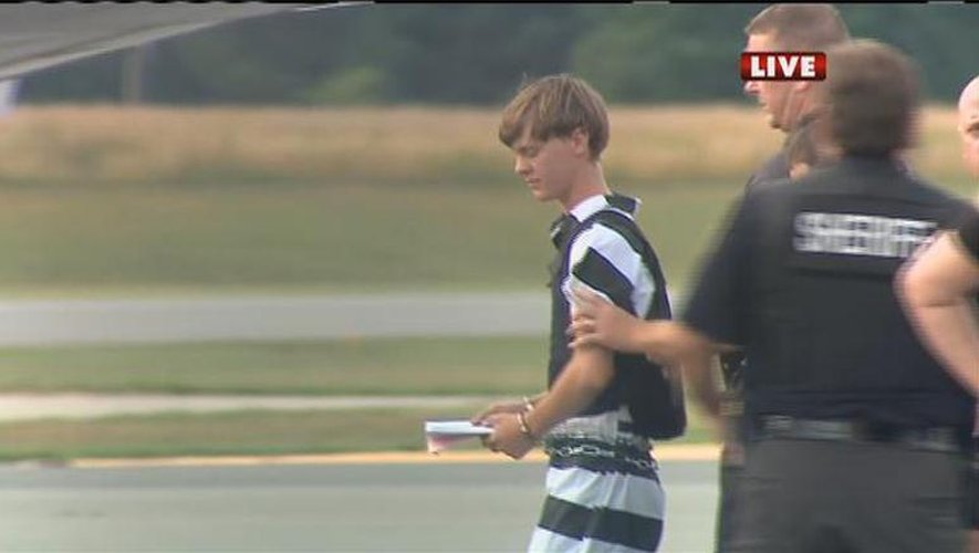 Capture d'écran de la chaîne WBTV News montrant l'auteur présumé de la tuerie de Charleston, Dylann Roof (en combinaison rayée), escorté par la police à l'aéroport du comté de Shelby, en Caroline du Nord, après son arrestation le 18 juin 2015