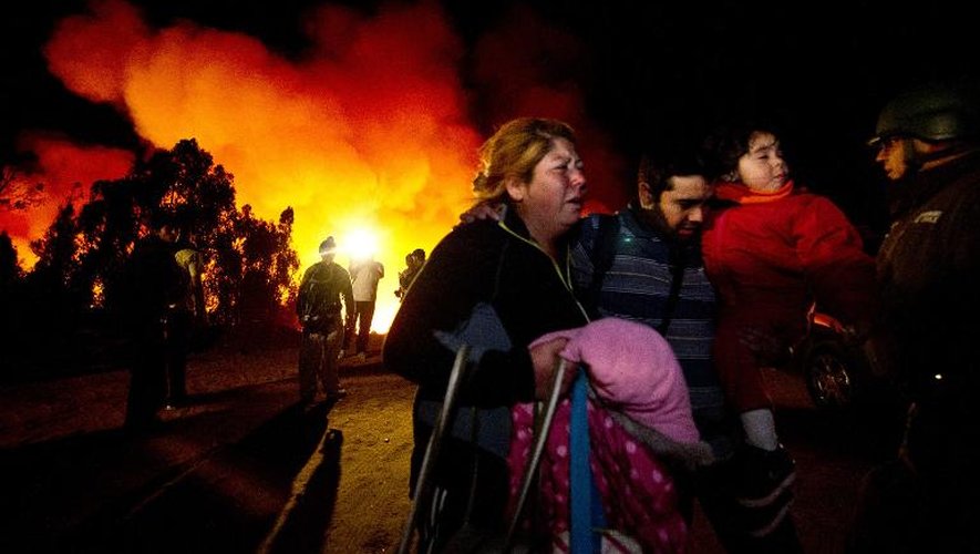 Des habitants fuient leur quartier ravagé par les flammes le 13 avril 2014 à Valparaiso