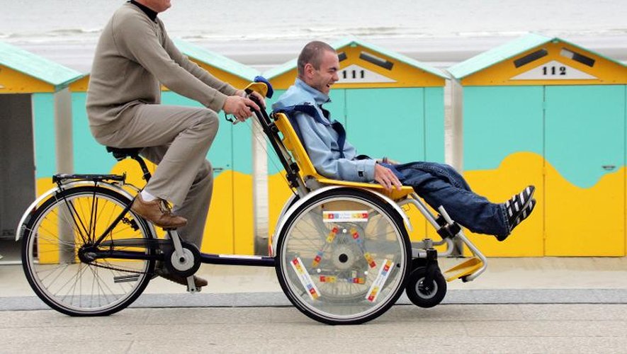 Un éducateur promène une personne handicapée sur un "vélo-pousse" afin de goûter aux joies de la plage, le 12 juillet 2007 sur la plage de Malo-les-Bains près de Dunkerque