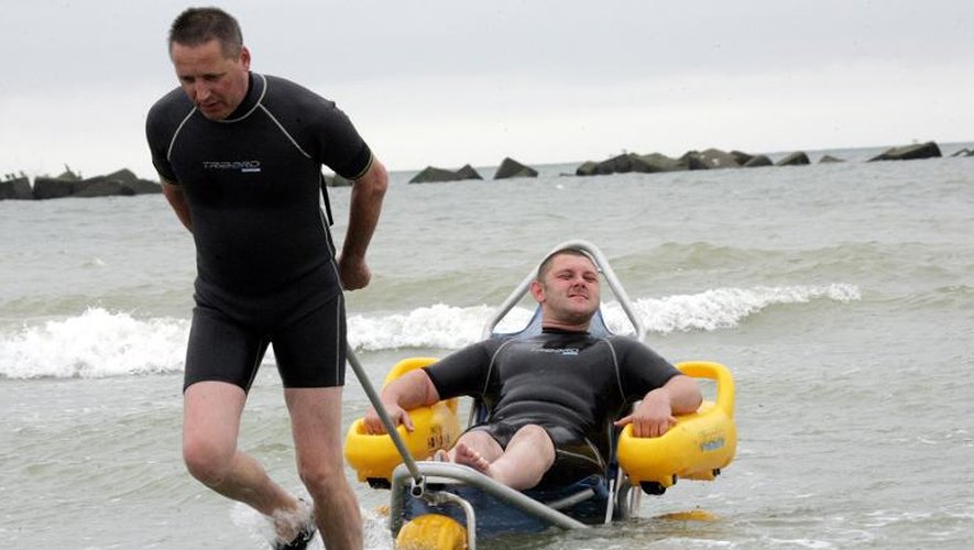Un éducateur aide une personne handicapée à prendre un bain de mer avec un "tiralo", le 12 juillet 2007 sur la plage de Malo-les-Bains près de Dunkerque