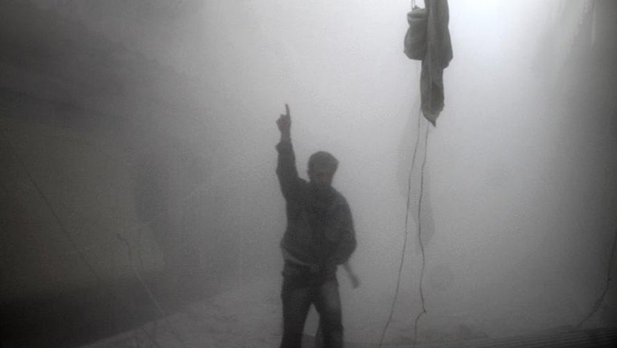 Un Syrien dans la poussière et la fumée après des bombardements aériens des forces gouvernementales à Alep, dans le quartier Ansari, dans le sud-ouest de la ville, le 15 avril 2014