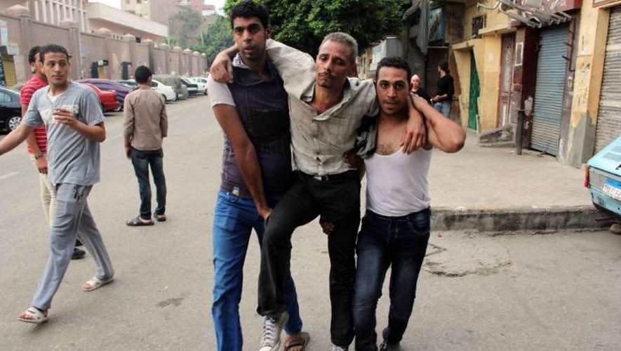 Deux hommes aident un camarade blessé lors de heurts avec des partisans du président égyptien Mohamed Morsi, le 3 juillet 2013  au Caire