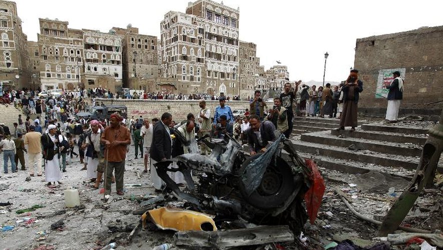 Des Yéménites autour de la carcasse de la voiture piégée qui a explosé le 20 juin 2015 devant une mosquée chiite à Sanaa