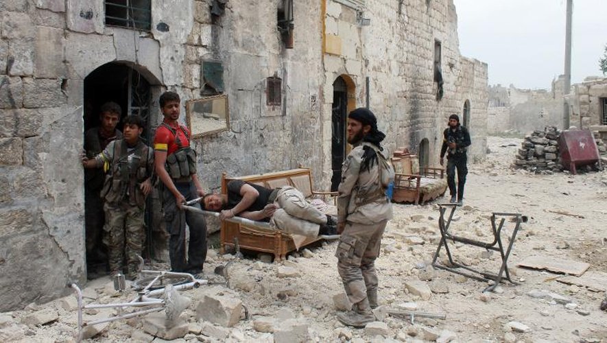Des membres de l'opposition au régime syrien évacuent des blessés à Alep, le 17 avril 2014