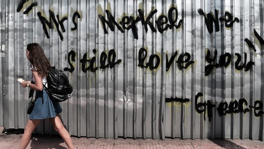 Une jeune fille passe le 19 mai 2015 devant un mur d'Athènes portant un graffiti qui dit: "Mme. Merkel, nous vous aimons toujours - Signé: Grèce"