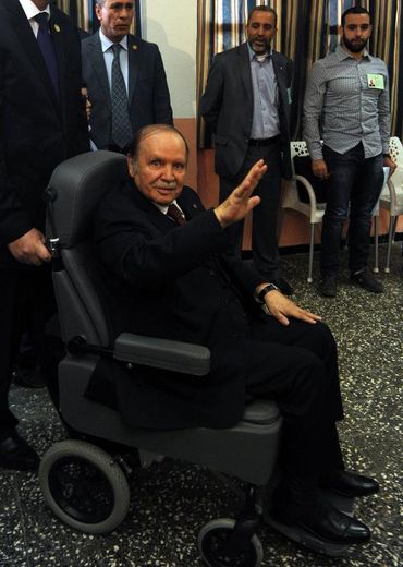 Abdelaziz Bouteflika salue la presse à son arrivée en fauteuil roulant le 17 avril 2014 dans un bureau de vote à Alger