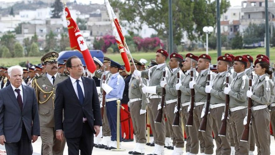 Le ministre tunisien de la Défense nationale Rachid Sabbagh (g) et le président français François Hollande (d) passent en revue la garde d'honneur au mausolée des martyrs de Sijoumi, à Tunis, le 5 juillet 2013