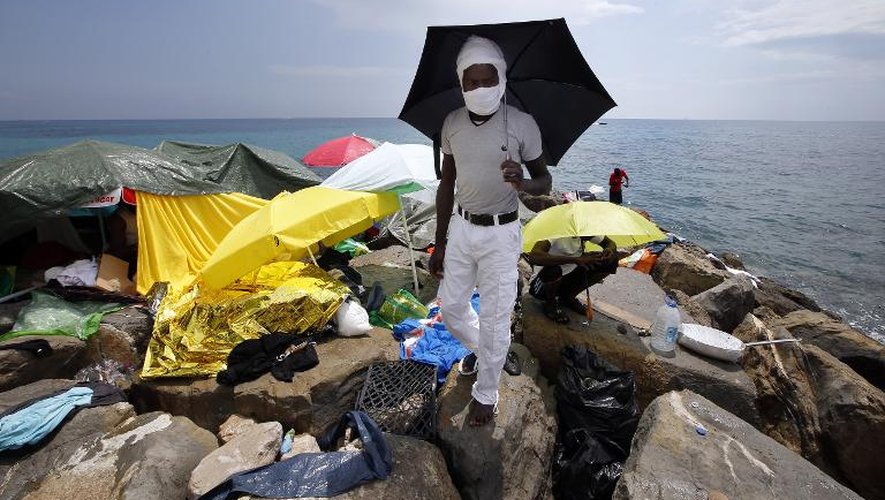 Des migrants se protègent du soleil sous des ombrelles au bord de la mer à Vintimille, une ville italienne frontalière de la France, le 20 juin 2015