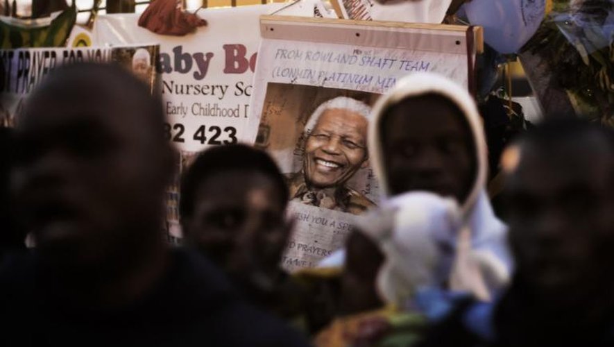 Une photo de Mandela au milieu de personnes priant le 2 juillet 2013 devant l'hôpital où se trouve Mandela à Pretoria