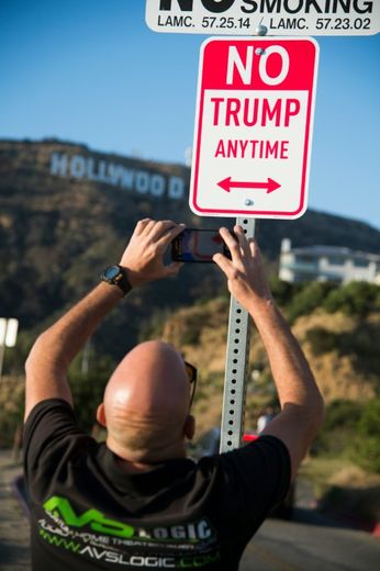 Un homme photographie une oeuvre du "street artist" Plastic Jesus, détournement d'un panneau d'interdiction de stationnement où figure "interdit à Trump à toute heure", à Hollywood en Californie le 27 avril 2016