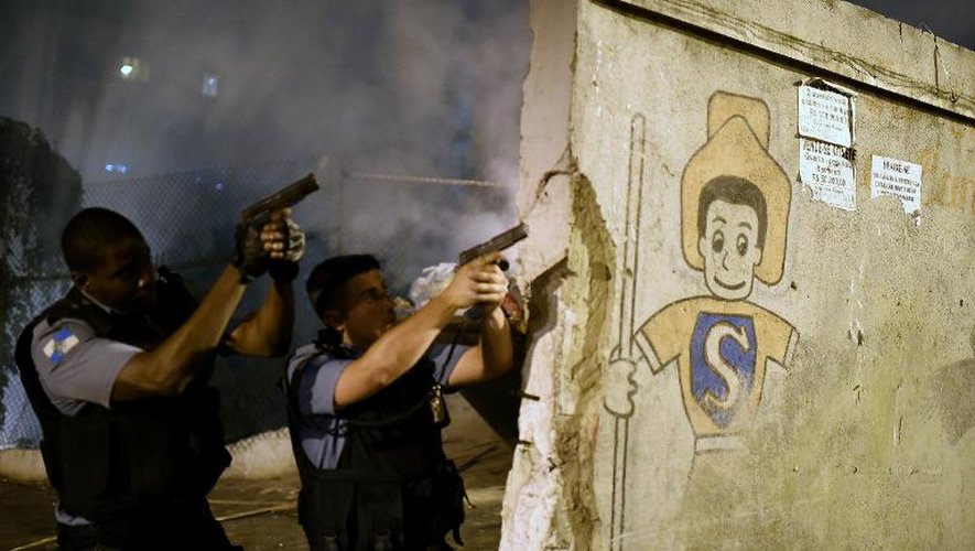 A Copacabana, des policiers en position de tir durant les émeutes qui ont secoué une favela à la suite de la mort d'un de ses jeunes habitants, le 22 avril 2014