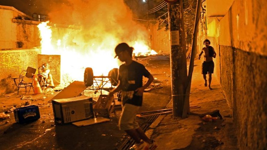 A Rio de Janeiro, des habitants courent dans les rues d'une favela près du quartier touristique de Copacabana, où se sont déclenchées de violentes émeutes le 22 avril 2014, à moins de deux mois de l'ouverture de la Coupe du monde de foot