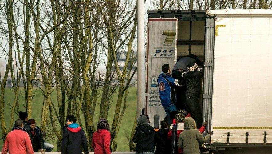 Des migrants montent dans un poids-lourd le 17 décembre 2016 à Calais pour se rendre clandestinement en Grande-Bretagne