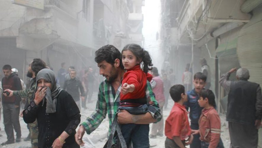 Des Syriens dans la ville d'Alep en Syrie, juste après des raids aériens, le 15 avril 2014