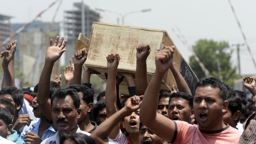 Des ouvriers portent en colère un cercueil symbolique, lors d'une manifestation le 23 avril 2014 à Dacca, un an après le drame du Rana Plaza