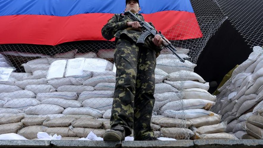 Un homme en tenu militaire tient la garde devant un bâtiment occupé par les pro-russes, le 24 avril 2014 à Slaviansk