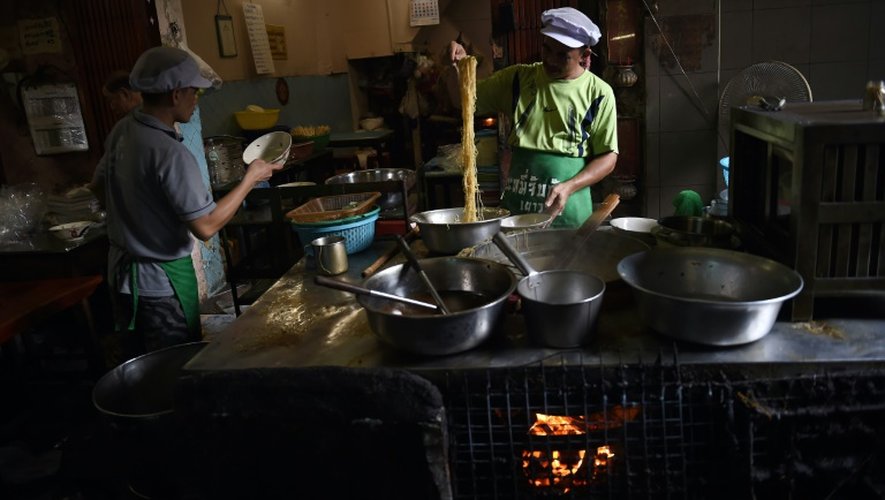 Des cuisiniers préparent des plats de nouilles dans une allée du quartier chinois de Bangkok le 12 avril 2016