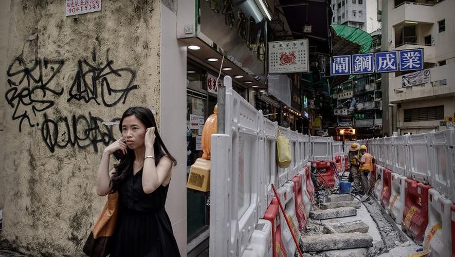 Une femme se couvre les oreilles face aux bruits des travaux dans une rue de Hong Kong, le 9 juillet 2013