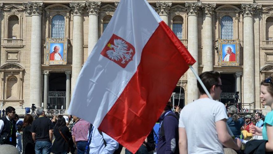 Un homme porte un drapeau polonais devant la Basilique St-Pierre au Vatican, le 25 avril 2014, où les pèlerins affluent