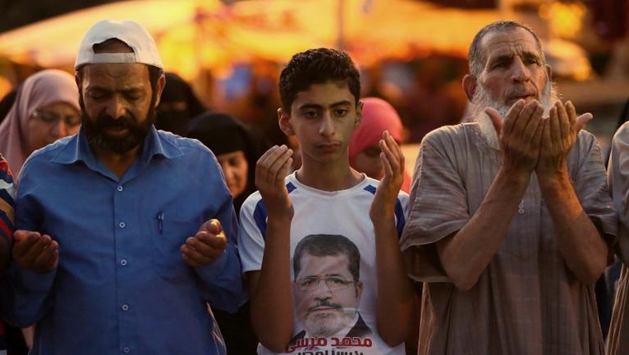 Des Egyptiens en prière, l'un portant un tee-shirt avec le portrai de Morsi, le 11 juillet 2013 au Caire