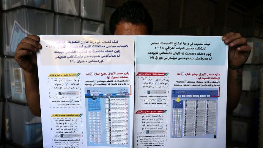 Un employé montre une affichette expliquant comment voter dans un centre électoral à Arbil en Irak le 26 avril 2014